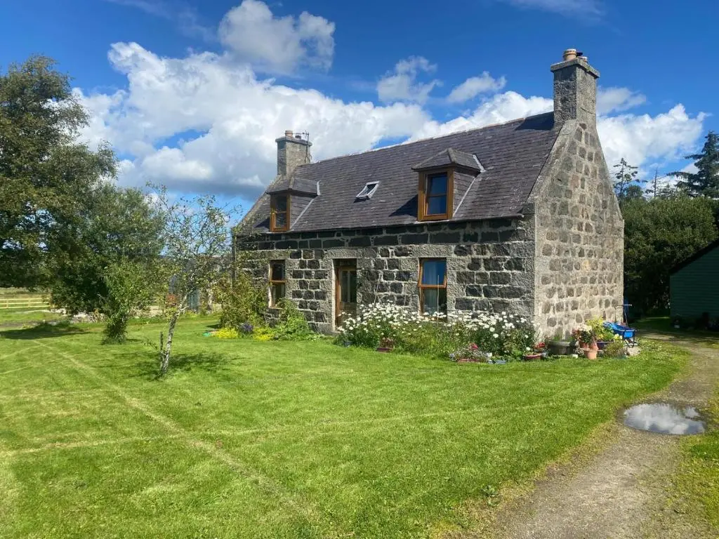 an old stone house on a grass field at Cottage Farmhouse in Huntly