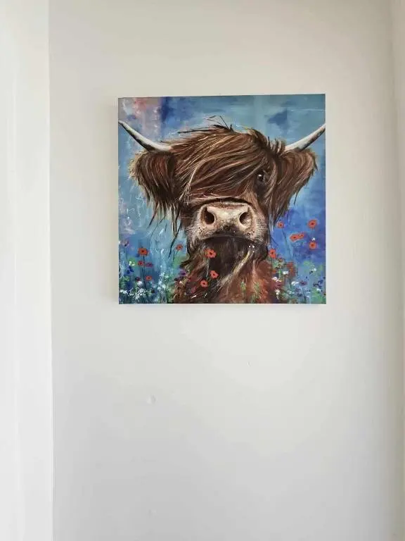 a painting of a cow on a wall at Owl View in Garve