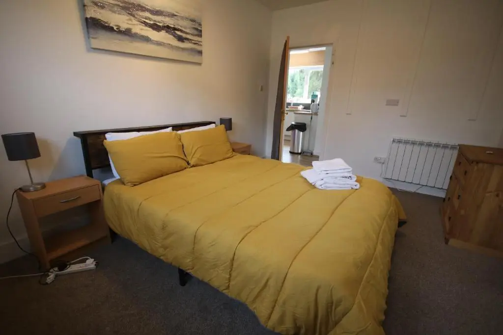 a bedroom with a bed with a yellow bedspread at Owl View in Garve