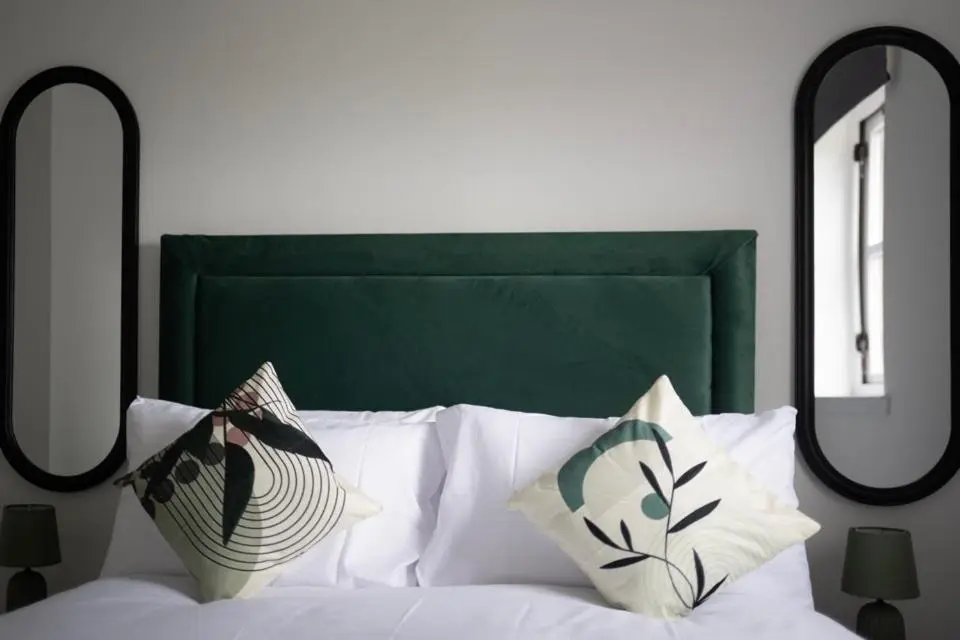 a bed with a green headboard and two mirrors at 1 BDR Apartment At Caledonia Luxe Stays Short Lets & Serviced Accommodation Inverness in Inverness