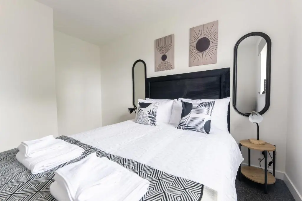 a bedroom with a white bed with black and white pillows at Dram Apartment in Inverness