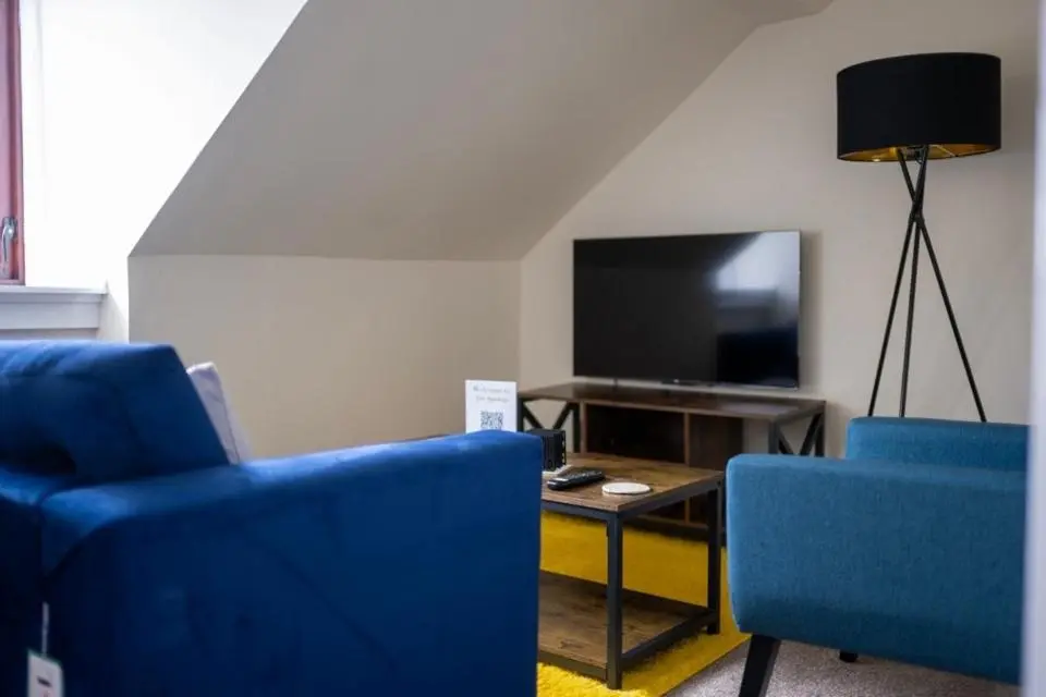 a living room with two blue chairs and a tv at 2 BDR Apt At Caledonia Luxe Stays Short Lets & Serviced Accommodation Inverness in Inverness