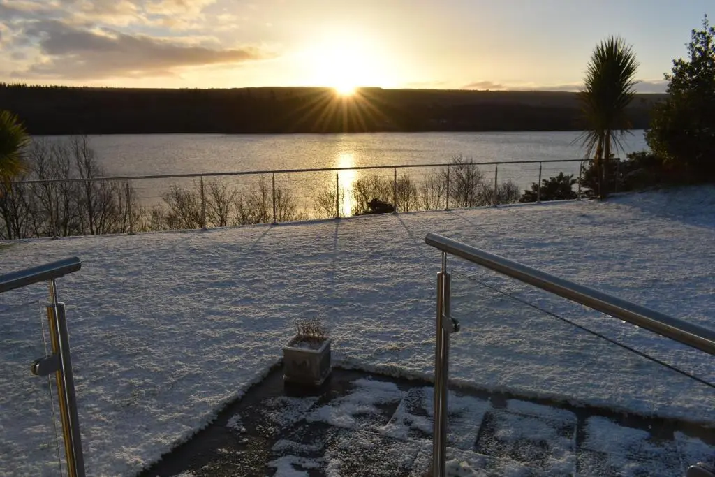 a swing in the snow with the sunset in the background at Kimcraigan B&B in Brackla
