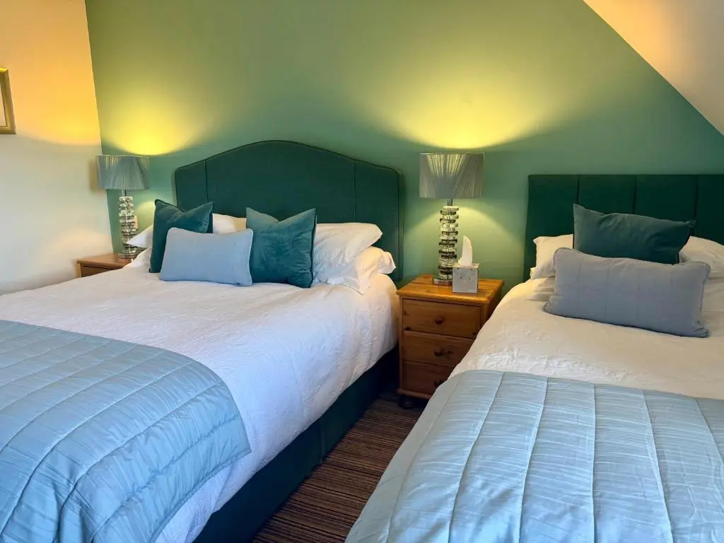 two beds in a bedroom with green walls at Kimcraigan B&B in Brackla