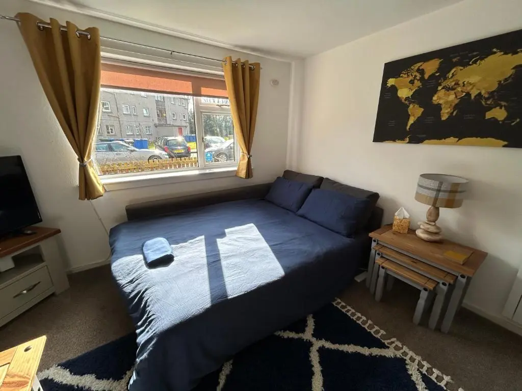 a bedroom with a blue bed and a window at Cosy Flat Close to City Centre Ideal for Families in Dalneigh