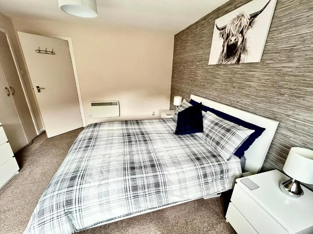 a bedroom with a bed and a picture of a cow on the wall at Cosy Flat Close to City Centre Ideal for Families in Dalneigh