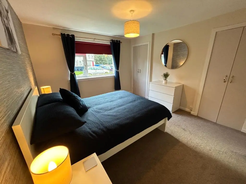 a bedroom with a black bed and a window at Cosy Flat Close to City Centre Ideal for Families in Dalneigh