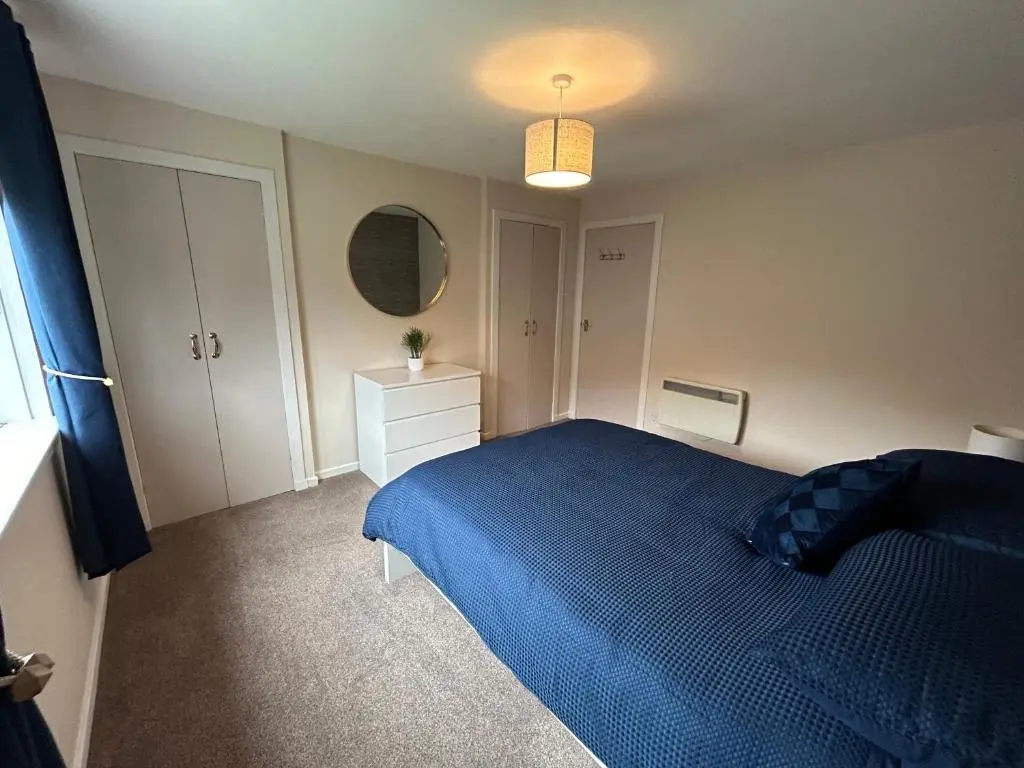 a bedroom with a blue bed and a mirror at Cosy Flat Close to City Centre Ideal for Families in Dalneigh