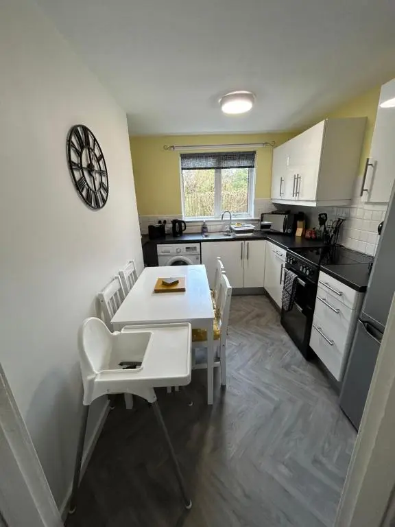 a small kitchen with a white table and chairs at Cosy Flat Close to City Centre Ideal for Families in Dalneigh