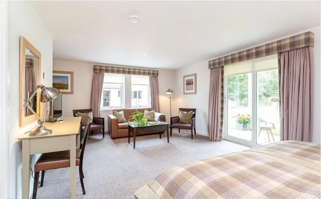 a hotel room with a bed and a living room at Sandown House in Nairn