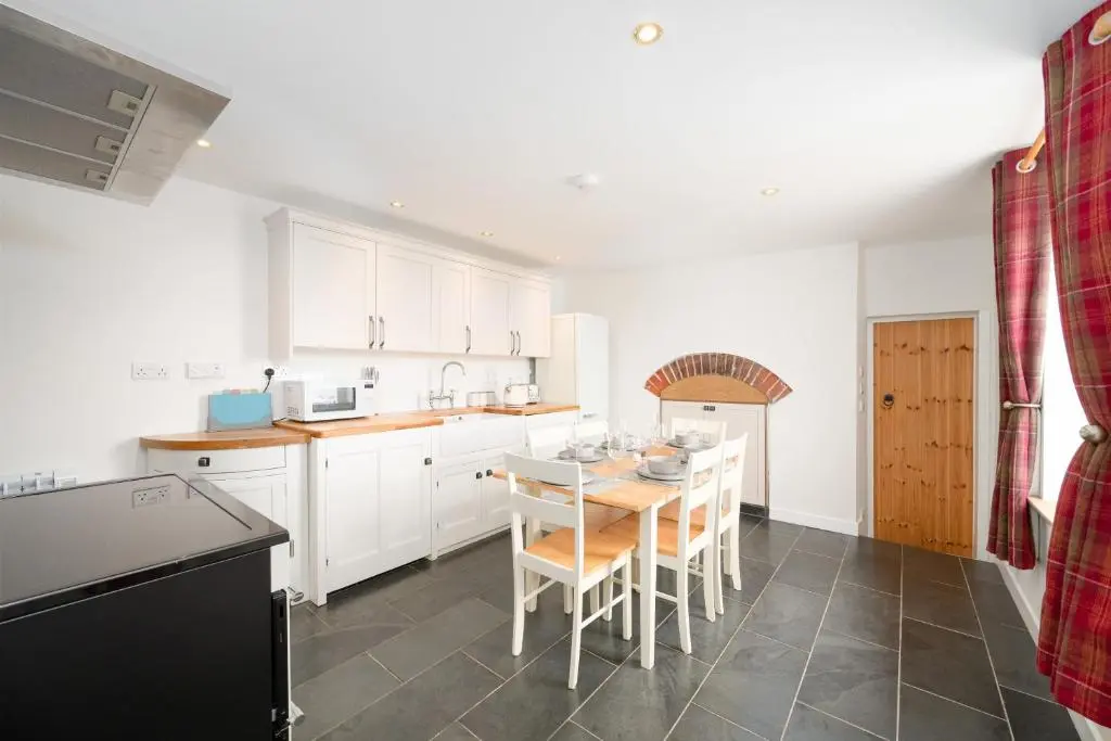 a kitchen with white cabinets and a table and chairs at Soundwaves, Seatown, Gardenstown in Gardenstown