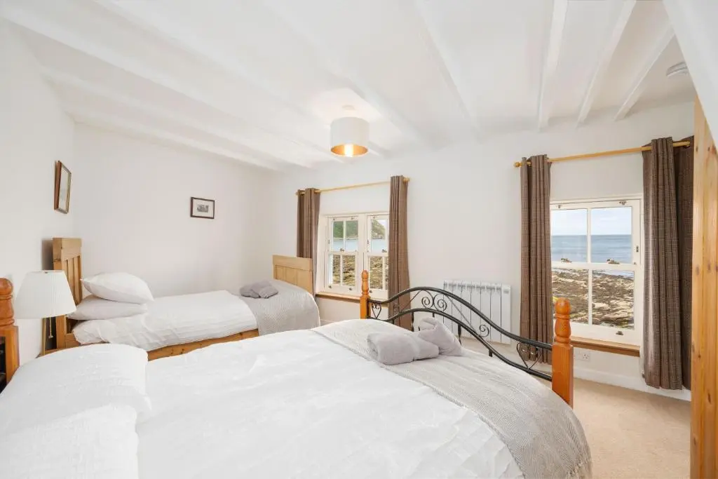 two beds in a bedroom with a view of the ocean at Soundwaves, Seatown, Gardenstown in Gardenstown