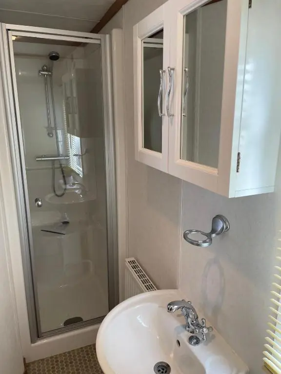 a bathroom with a sink and a glass shower at Number 28 Dornoch Firth Caravan Park in Dornoch