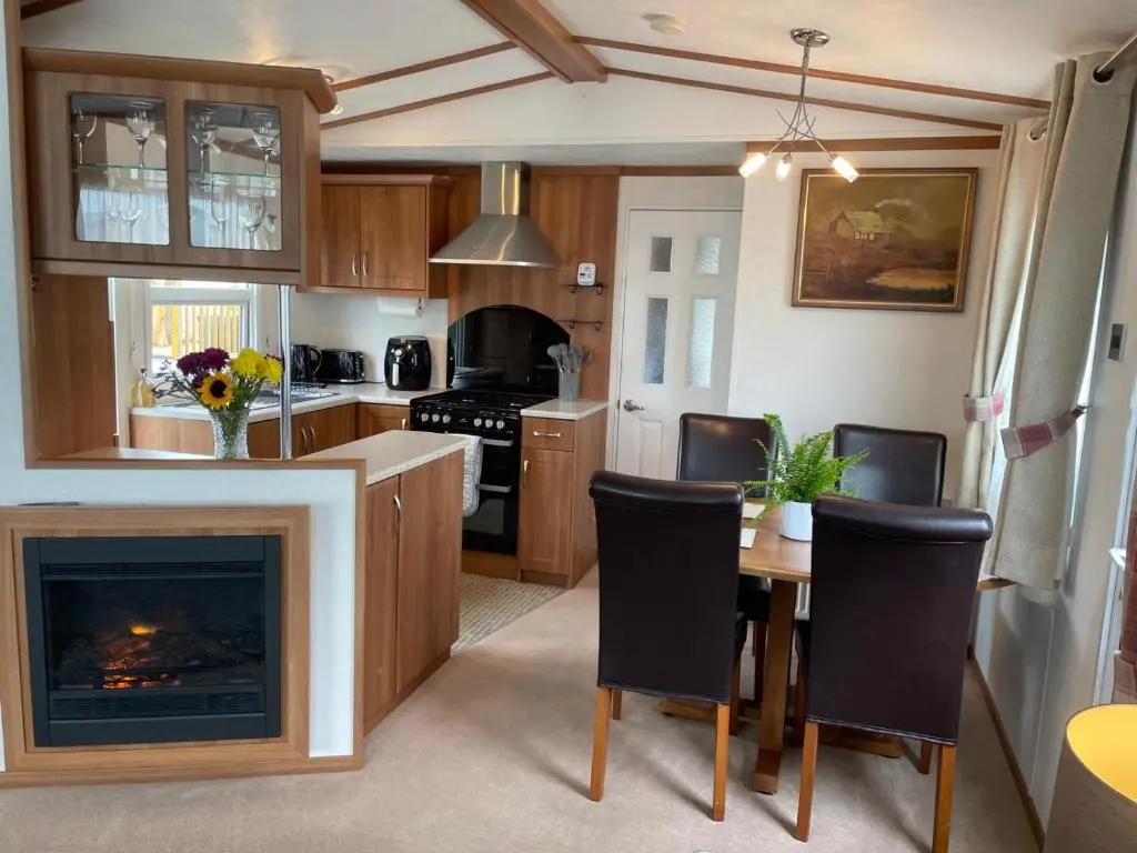 a kitchen with a fireplace and a table and chairs at Number 28 Dornoch Firth Caravan Park in Dornoch