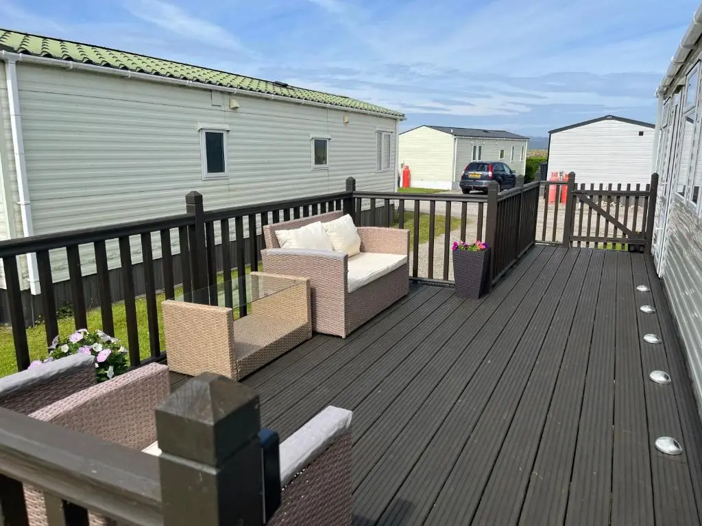 a deck with two chairs and a couch on it at Number 28 Dornoch Firth Caravan Park in Dornoch