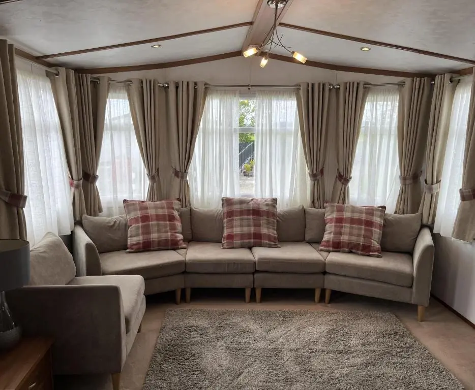 a living room with a couch and some windows at Number 28 Dornoch Firth Caravan Park in Dornoch
