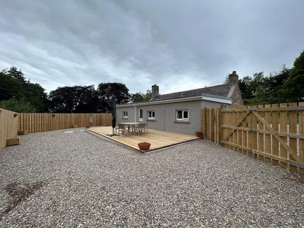 a backyard with a wooden fence and a house at Burnside Cottage in Fochabers