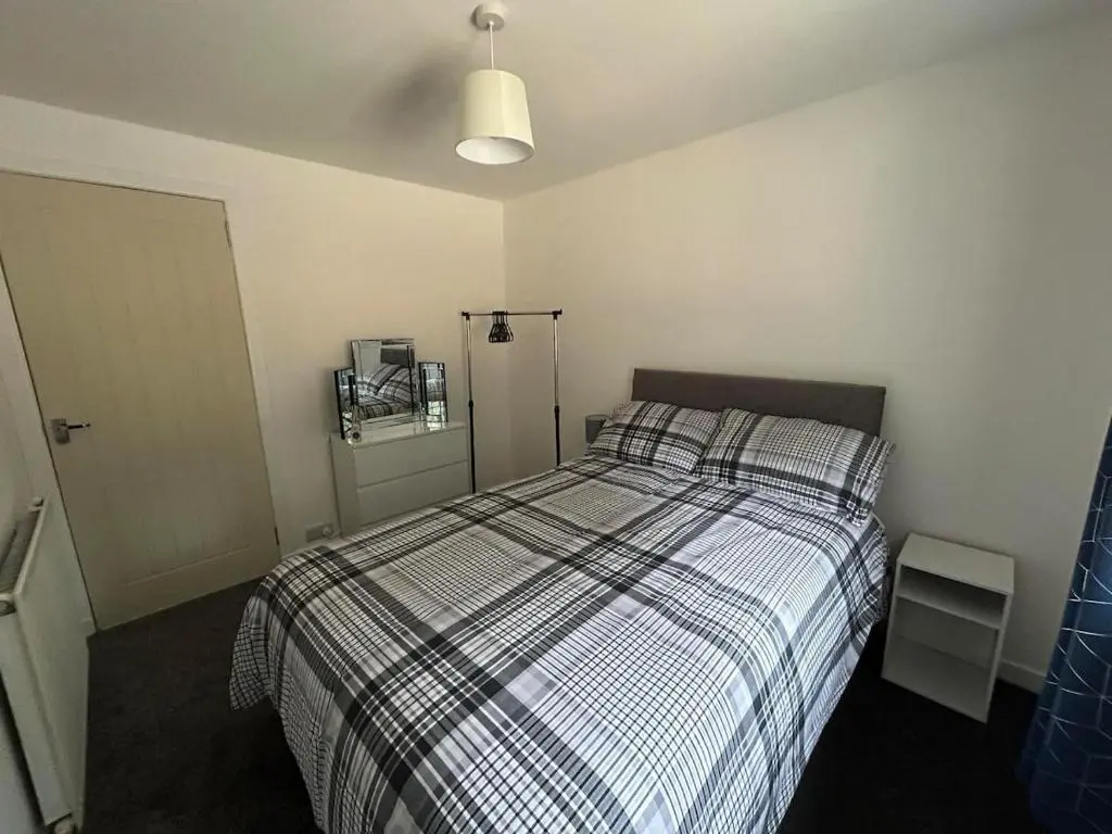 a bedroom with a bed with a checkered blanket at Burnside Cottage in Fochabers
