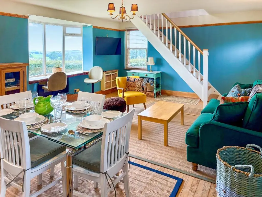 a living room with a table and a green couch at The Cottage At Mains House in Tain