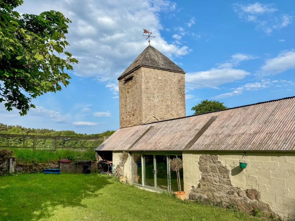 an old stone building with a cross on top of it at The Cottage At Mains House in Tain