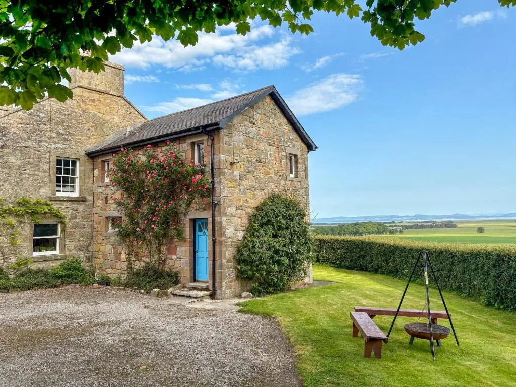 an old stone house with a swing in front of it at The Cottage At Mains House in Tain