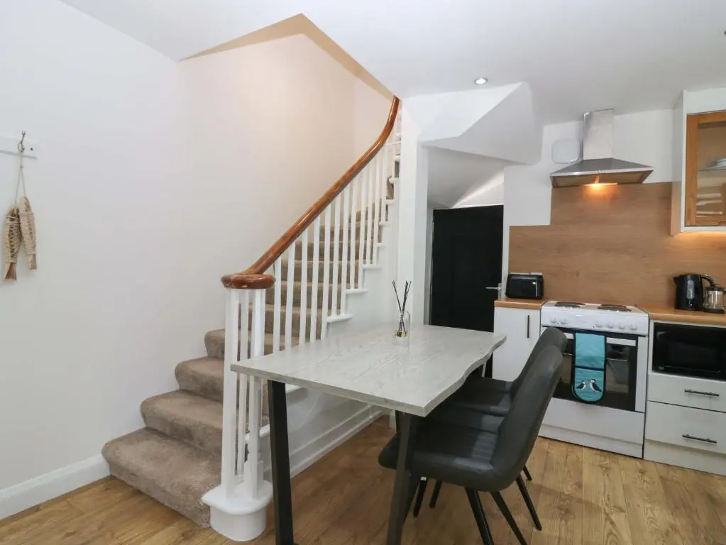 a kitchen and dining room with a table and a staircase at 3 Caroline Place in Fraserburgh