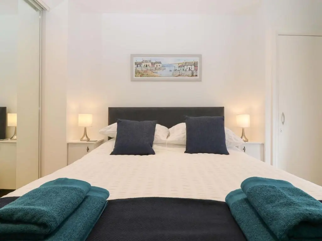 a bedroom with a large white bed with blue pillows at 3 Caroline Place in Fraserburgh