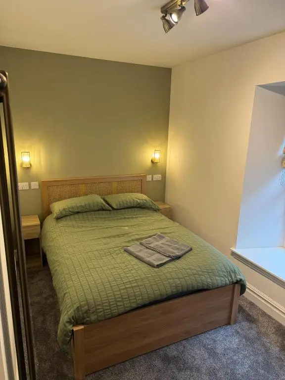 a bedroom with a bed with a green comforter at Luxury central townhouse in Wick