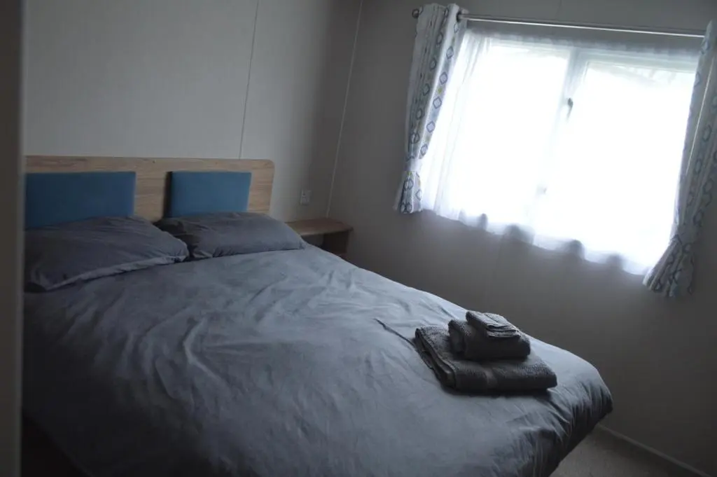 a bedroom with a bed with a blanket and a window at B9 at The Old Mill Holiday Park in Dyke