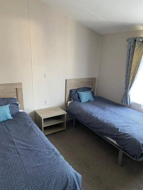 a bedroom with two beds and a window at Clearwater Lodge in Lossiemouth
