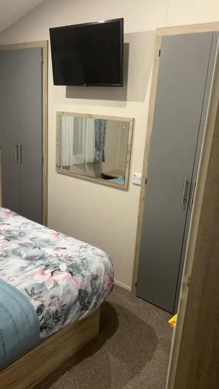 a bedroom with a bed and a flat screen tv at Clearwater Lodge in Lossiemouth
