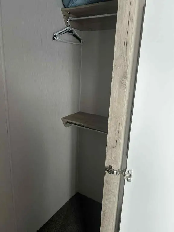 a room with a closet with a wooden door and shelves at Clearwater Lodge in Lossiemouth
