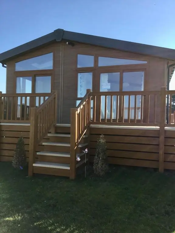 a small cabin with a staircase and a deck at Rivendale Lodge in Burghead