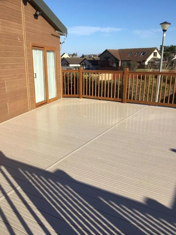 a deck with a wooden fence and a house at Rivendale Lodge in Burghead