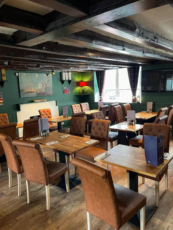 a dining room with wooden tables and chairs at Crown and Anchor Inn in Findhorn