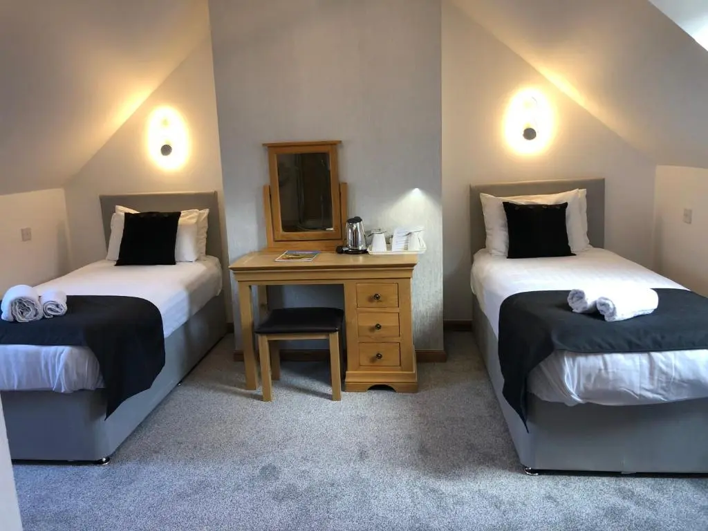 a room with two beds and a table with a mirror at Druid House B&B in Inverness