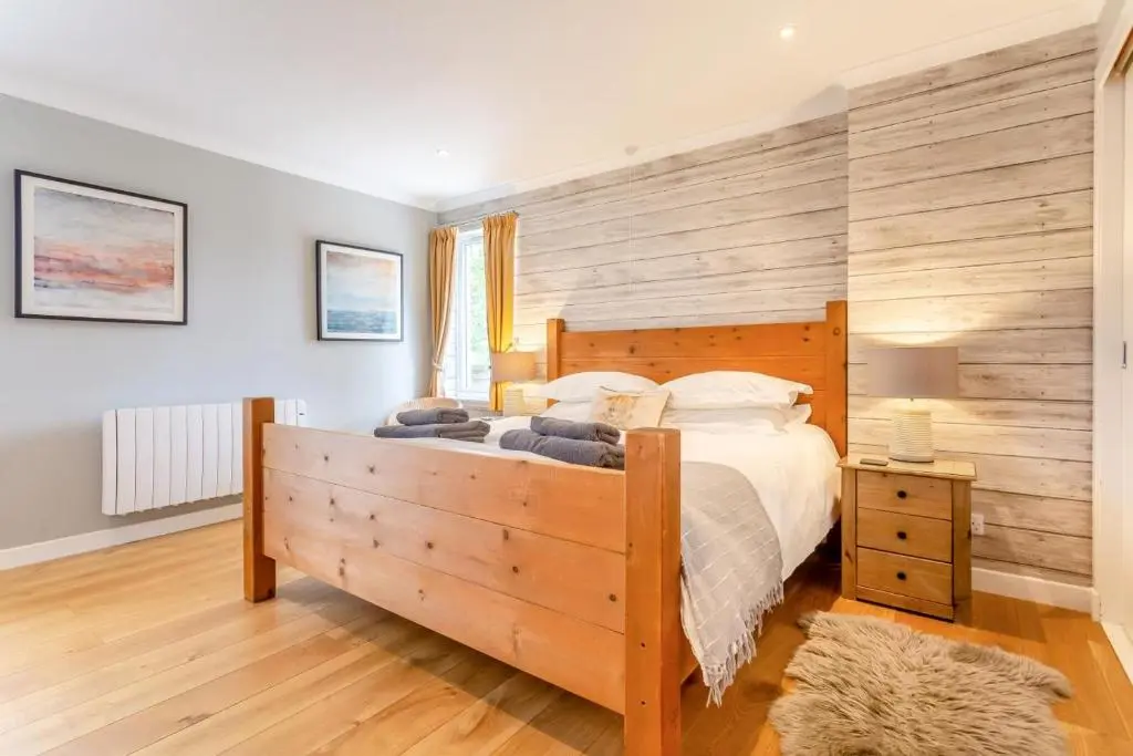 a bedroom with a large bed and a wooden wall at 1 Bed in Newtonmore oc-a32412 in Newtonmore