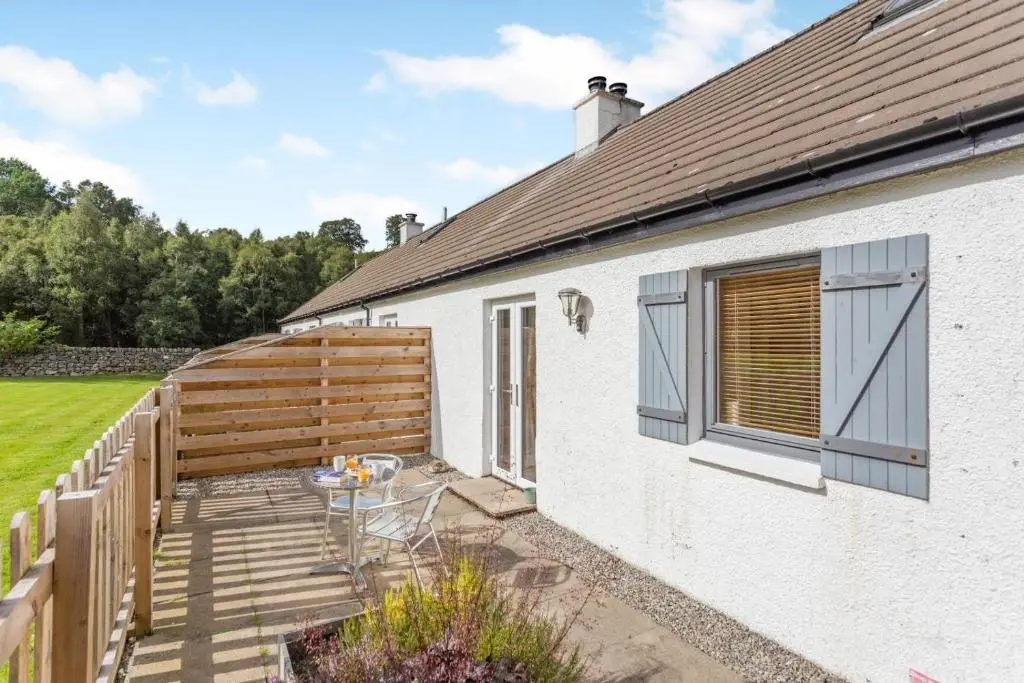 a patio of a white house with a wooden fence at 1 Bed in Newtonmore oc-a32412 in Newtonmore