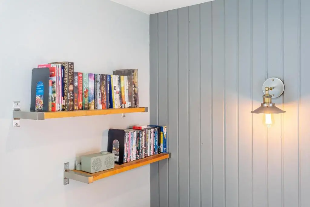 a book shelf with books and a light on a wall at 1 Bed in Newtonmore oc-l32415 in Newtonmore