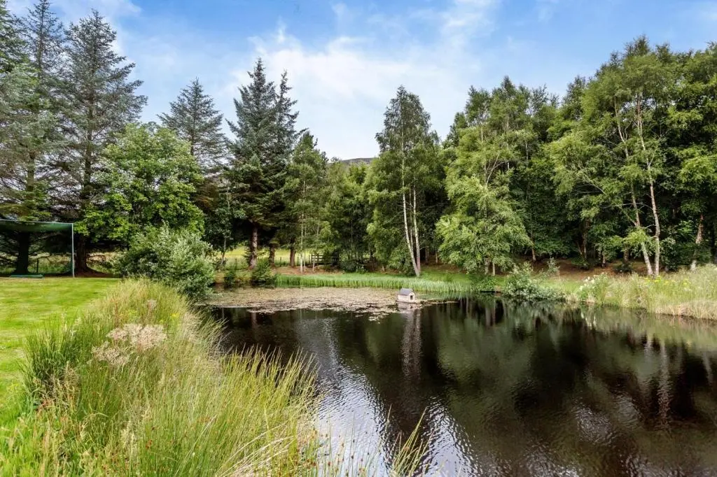 a pond in a park with a boat in the water at 1 Bed in Newtonmore oc-l32415 in Newtonmore