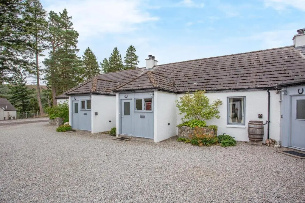 a white house with a gravel driveway in front of it at 1 Bed in Newtonmore oc-b32417 in Newtonmore