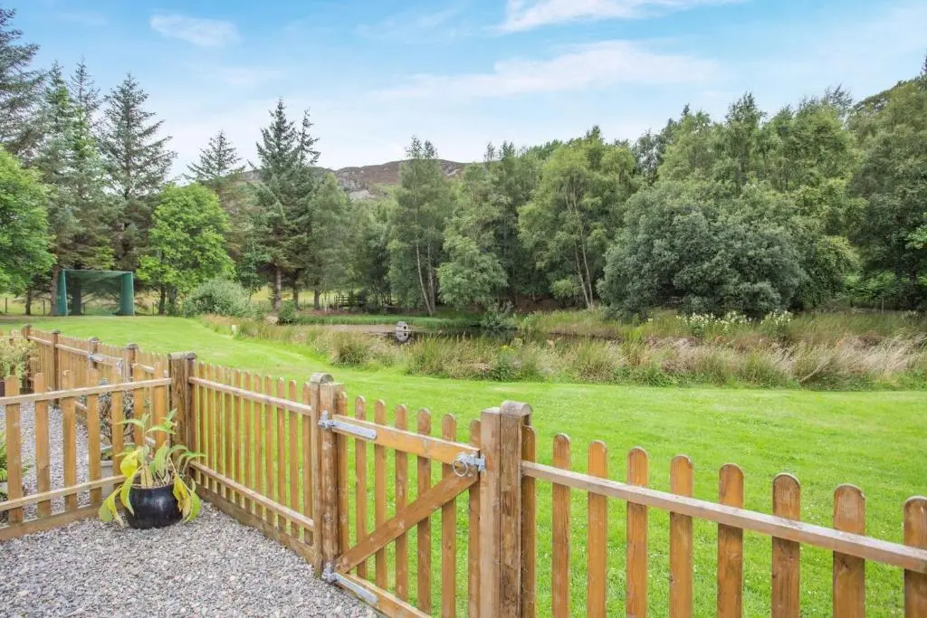 a wooden fence with a field in the background at 2 Bed in Newtonmore oc-e32418 in Newtonmore