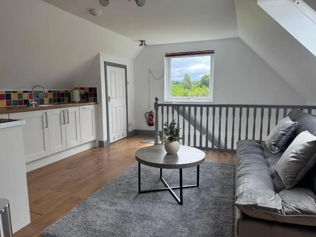 a living room with a couch and a table at Daviot Lodge apartment in Daviot