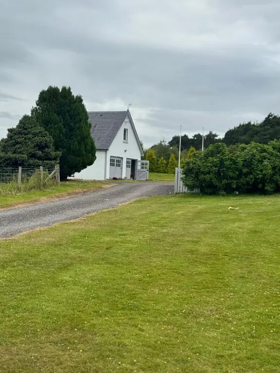 a white house sitting on the side of a road at Daviot Lodge apartment in Daviot