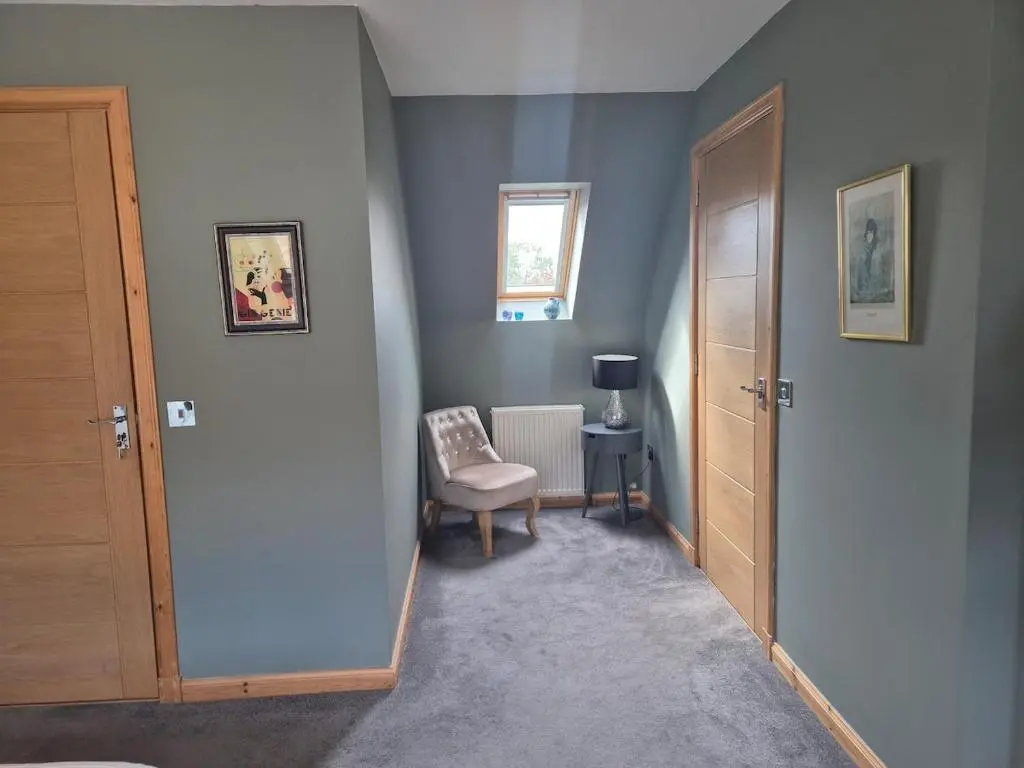 a hallway with a door and a chair and a window at 2 Bed House - free parking, short walk to City centre in Inverness