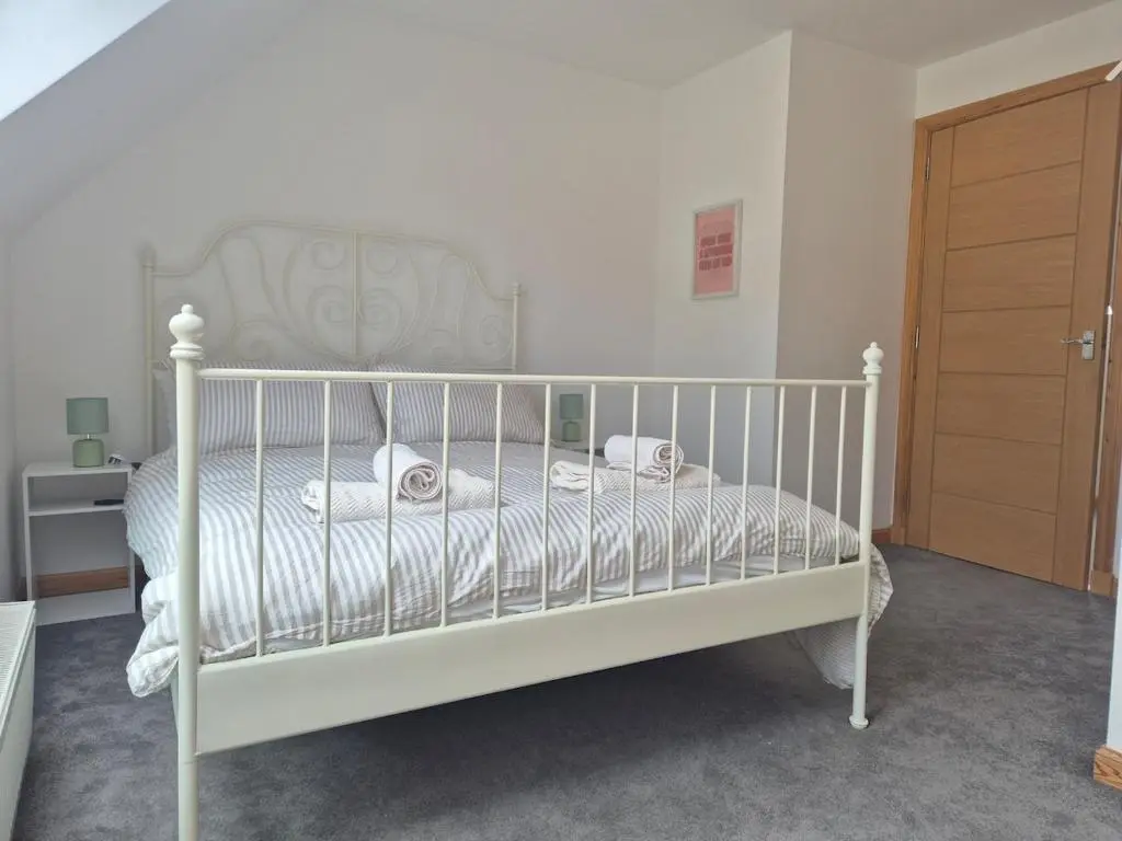 a bedroom with a white bed and a wooden door at 2 Bed House - free parking, short walk to City centre in Inverness