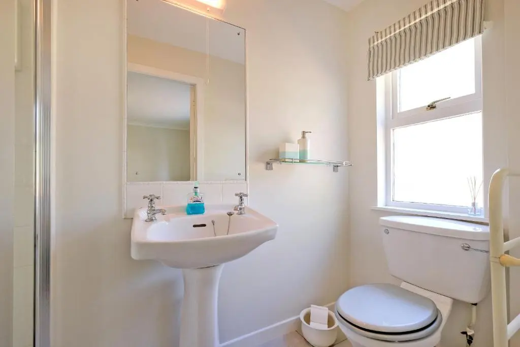 a bathroom with a sink and a toilet and a mirror at Finest Retreats - Corrennie School Cottage in Inverurie