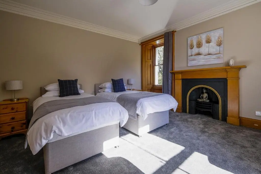 a bedroom with two beds and a fireplace at Gledfield Estate Holiday Cottages in Lower Gledfield