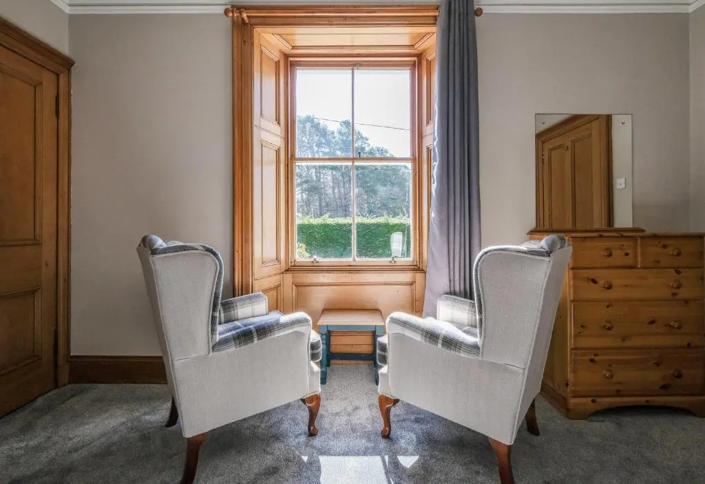 two chairs in a room with a window and a dresser at Gledfield Estate Holiday Cottages in Lower Gledfield