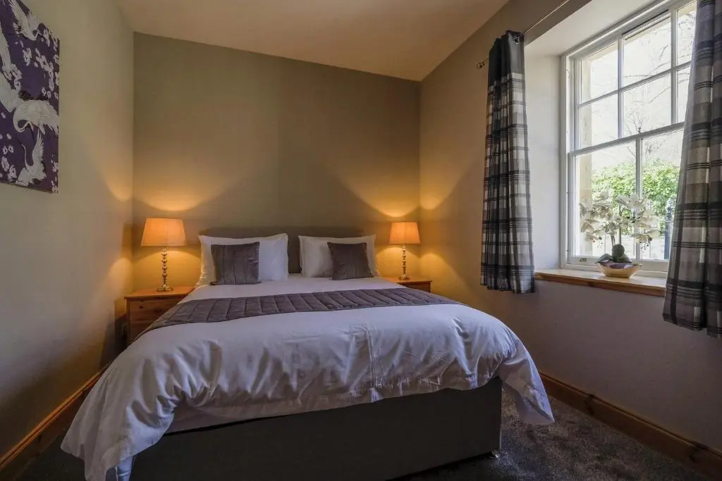 a bedroom with a bed with two lamps and a window at Gledfield Estate Holiday Cottages in Lower Gledfield
